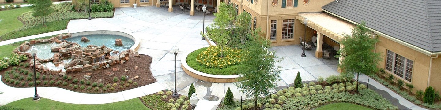 exterior shot of a clubhouse with a fountain pond and putting green