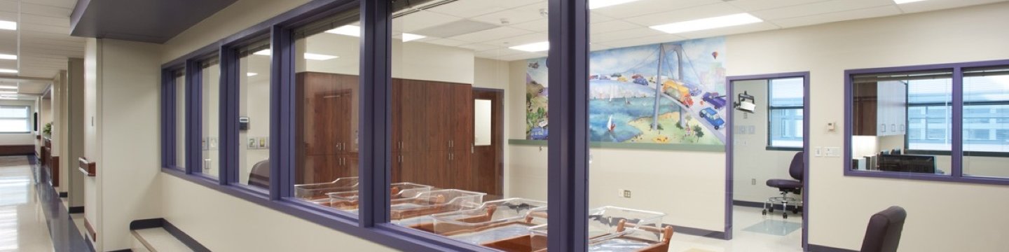 a wall of windows looking into a newborn nursery at a hospital