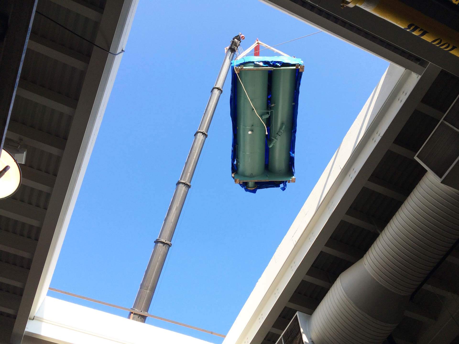 a crane lowering a chiller into a room